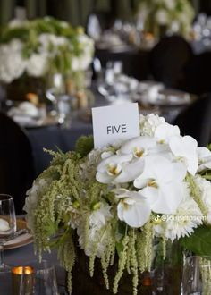 there is a vase with white flowers in it on the dining room table at this wedding reception