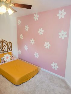 a bedroom with pink and white flowers painted on the wall, bed in foreground