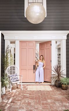 a woman standing in front of a pink door