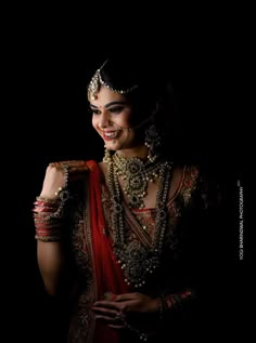 a woman in a red and gold bridal outfit with pearls on her head, smiling