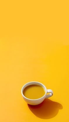 a cup of coffee sitting on top of a yellow table