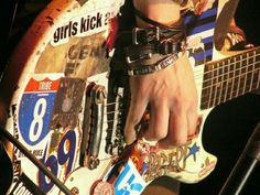 a close up of a person's hand on top of an electric guitar with stickers all over it