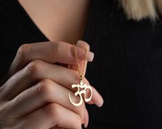 Discover inner peace with our Handmade Gold Aum Symbol Necklace, featuring a delicate pendant inspired by the sacred Om symbol. Meticulously crafted in two exceptional material options: 925 sterling silver and 14K solid gold, this necklace allows you to choose between classic elegance and the enduring warmth of gold. While the choice of materials is significant, the true essence lies in the profound symbolism of the Aum symbol. Whether you opt for the timeless allure of gold or the classic beauty of silver, this necklace is more than jewelry; it's a spiritual companion, a reminder of the universal sound that represents the essence of all creation. Each Aum Symbol Necklace is presented in an elegant gift box, ready to be shared on special occasions like birthdays, graduations, or any celebr Spiritual Pendant Necklaces As Gifts, Spiritual Round Pendant For Gift, Handmade Spiritual Necklaces For Gifts, Symbolic Pendant Charm Necklaces For Meditation, Symbolic Necklaces For Festivals, Spiritual Necklaces For Festivals And Gifts, Spiritual Necklaces For Gifts And Festivals, Spiritual Necklace For Festivals And Gifts, Spiritual Pendant Necklace