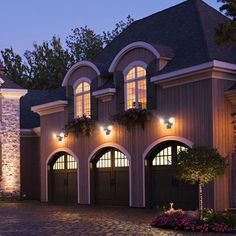 a large house lit up at night with lights on the garage doors and windows above it