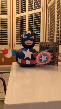 an inflatable captain america toy sitting on top of a table next to a book