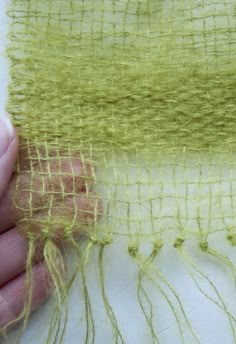 someone is stitching on the side of a piece of yellow fabric with two hands