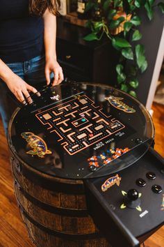 a woman playing a game on top of a wooden barrel with an arcade machine in it