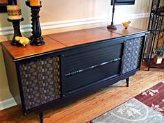 a black and brown sideboard sitting on top of a wooden floor next to a lamp