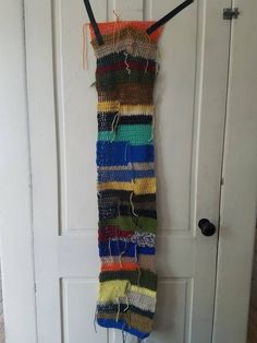 a multicolored scarf hanging on a door with hooks and strings attached to it