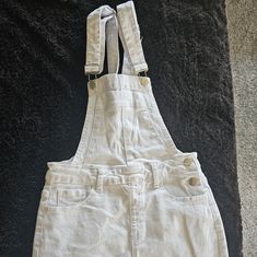 White Denim Overall Skirt. It Is A Short Skirt With Two Adjustable Straps And A Relaxed Fit. The Skirt Has Five Pockets, Two In The Front, Two In The Back, And One On The Chest. The Skirt Is A White Color And Is Made Of A Thick, Sturdy Denim Material. Never Worn. Size S Runs Small. Skirt Waist 13 1/2 Inch Skirt Length 15 1/2 Overalls Skirt, Skirt Overalls, Small Skirt, Overall Skirt, Denim Material, Short Skirt, White Denim, Skirt Length, White Color