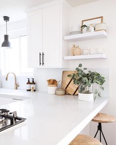 a kitchen with white counter tops and open shelves