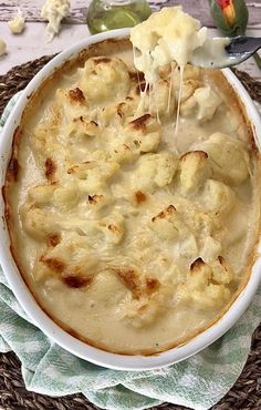 a white bowl filled with macaroni and cheese on top of a woven place mat