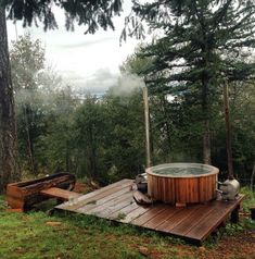 a hot tub sitting on top of a wooden platform in the woods next to trees