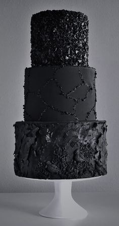 three tiered cake with black frosting and sprinkles