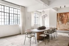 a dining room table with six chairs in front of a large painting on the wall