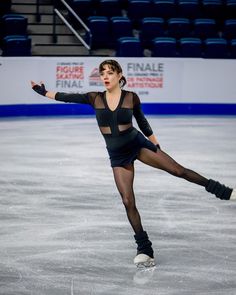 a woman skating on an ice rink in a black dress with sheer sleeves and tights