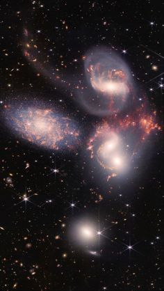 two spiral shaped objects in the middle of a dark sky filled with stars and dust