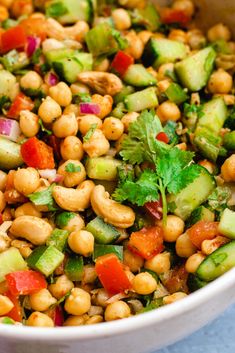 a white bowl filled with chickpeas, cucumber, and cilantro