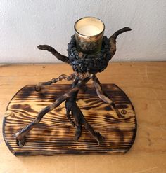 a candle holder made out of wood with branches on the base and a glass in it