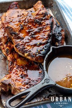 grilled pork chops in a cast iron skillet with sauce on the side