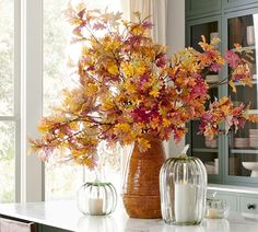 two vases filled with flowers on top of a counter next to candles and plates