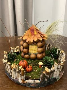 a small house made out of logs and leaves on top of a table with plants