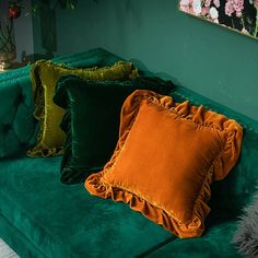 three pillows on a green couch in a living room