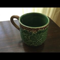 a green mug sitting on top of a wooden table