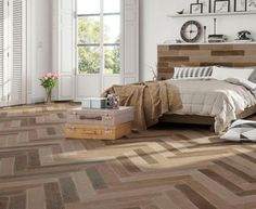 a bedroom scene with focus on the bed and wood flooring that looks like herringbones