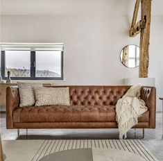 a brown leather couch sitting in a living room on top of a white carpeted floor