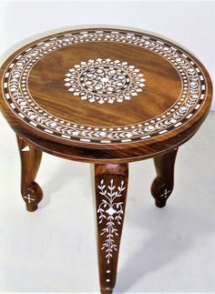 a small wooden table with white designs on it's top and bottom edge, sitting on a plain surface