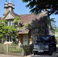 a black truck parked in front of a house with wistery vines on the roof