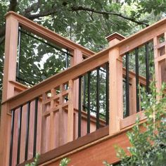 a wooden deck with railings and trees in the back ground, looking up at it