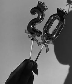 a person holding two balloons in the shape of numbers 50 and one with a crown on top