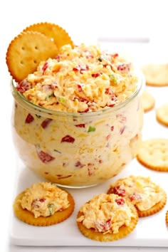 a glass bowl filled with crackers and dip next to crackers on a plate