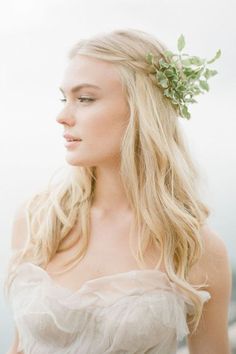 a woman with long blonde hair and a flower in her hair is wearing a white dress