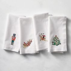 four embroidered christmas napkins on a white surface