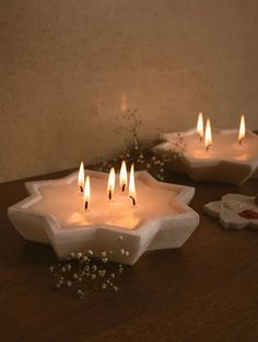 three white candles sitting on top of a wooden table