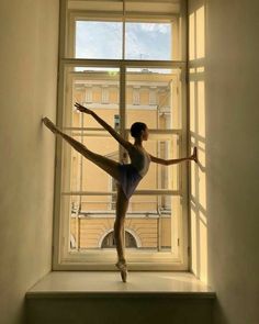 a ballerina standing on a ledge in front of a window with her arms stretched out