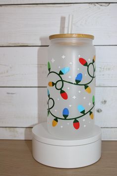 a glass jar with lights on it sitting on top of a white stand next to a wooden wall