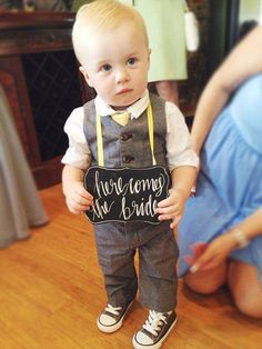 a little boy holding a sign that says, we're home for the bride