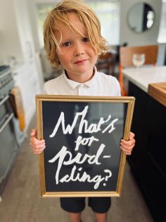 a little boy holding up a sign that says what's for bird - telling?