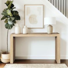 there is a plant on the table in front of the stair case and framed pictures