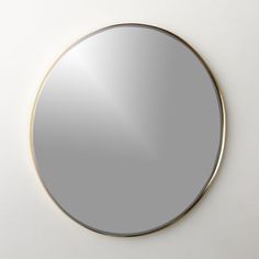 a round mirror on the wall with gold trim around it's edges and bottom edge