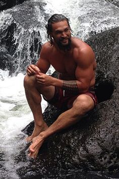 a man sitting on top of a rock in front of a river filled with water