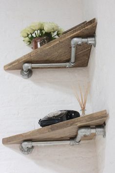 two wooden shelves with metal pipe brackets on the top and one shelf has a flower pot in it