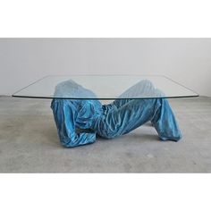 a person laying on the ground under a glass table with blue cloth covering it's legs