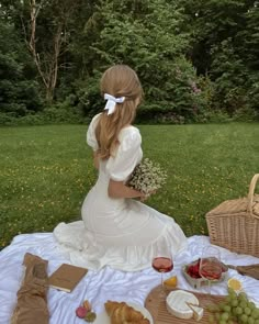 a woman sitting at a picnic table with food and wine in front of her,