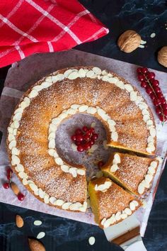 a cake is being cut with a knife and surrounded by almonds, cherries, and powdered sugar