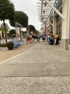 people are walking down the sidewalk in front of shops